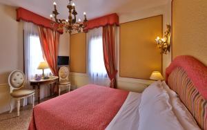a bedroom with a red bed and a desk and a table at Hotel Arlecchino in Venice