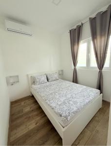 a white bedroom with a bed and two windows at Apartmani Home in Zaječar +12 photos