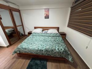 a bedroom with a bed with a green blanket at Green Life Apartment in Sakumona