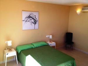 sypialnia z zielonym łóżkiem i 2 szafkami nocnymi w obiekcie Ático Ancla w mieście L'Ametlla de Mar