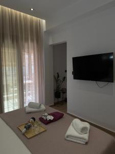 a room with a bed with towels and a flat screen tv at Nido Estivo 1 in Nea Skioni