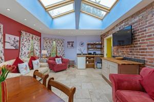 a living room with red walls and a skylight at Roundabout Farm in Thurning