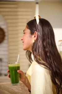 a woman holding a green drink in a glass at TheLifeCo Sharm El Sheikh in Sharm El Sheikh