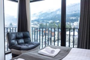 a bed and a chair in a room with a balcony at Mestia HOTEL AMIRANI in Mestia