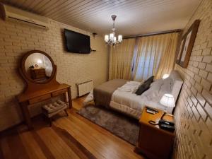 a bedroom with a bed and a mirror and a table at Hotel Vovó Carolina in Gramado