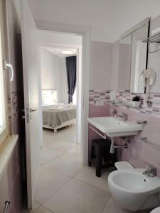 a bathroom with a sink and a toilet and a bed at OndaMaris Tropea in Tropea +62 photos