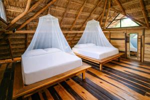 two beds in a thatched room with windows at Treehouse Tulum H2Ojos in Tulum