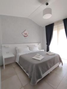a white bedroom with a bed with two towels on it at OndaMaris Tropea in Tropea