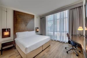 a hotel room with a bed and a desk and window at Radisson Blu Hotel, Dubai Barsha Heights in Dubai