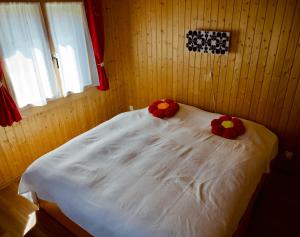 a bedroom with a white bed with two pillows on it at Chalet Enzian Wirzweli in Dallenwil