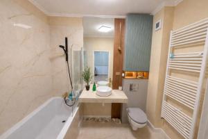 a bathroom with a tub and a sink and a toilet at Ophir Apartment Ultracentral,the greenest and brightest central area,3 parking space in the large yard in Cluj-Napoca