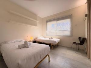 a bedroom with two beds and a window and a chair at Life Apartments Costa Ballena in Costa Ballena +161 photos