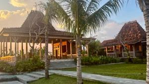 a house with palm trees in front of it at Casa Tibubiu in Tabanan