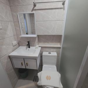 a bathroom with a toilet and a sink and a mirror at Sunflower Residences Capitol in Cebu City