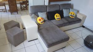 a couch with three simpsons pillows on it at Maison, jardin, barbecue et vélo classé 3 étoiles in Dives-sur-Mer