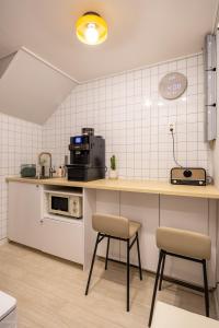 a kitchen with a counter and two stools in it at GreeneStay Sindang DDP Seoul in Seoul