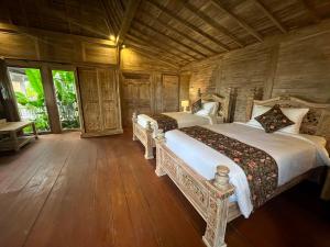 a bedroom with two beds and a wooden ceiling at Casa Tibubiu in Tabanan