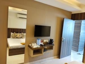 a bedroom with a bed and a tv on the wall at Eennra Kaansabbati in Medinīpur