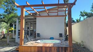 a patio with a hot tub and a wooden pergola at Casa Aconchegante in Bertioga