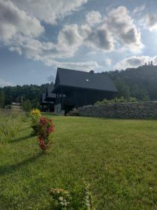 a large building with a stone wall in a field at Domki BIERWIONO in Cisna