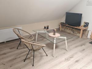 a living room with a table and two chairs and a television at Le refuge du chat endormi in Goderville