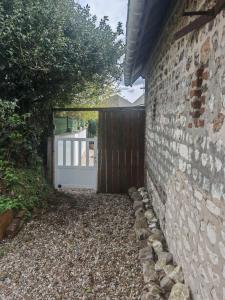 a brick wall with a gate and a driveway at Le refuge du chat endormi in Goderville +2 photos