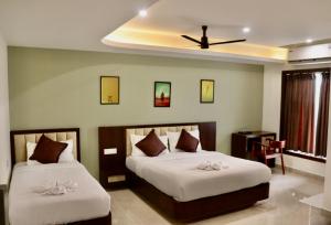 a bedroom with two beds and a table and a ceiling at Waves Residency in Chennai