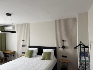 a bedroom with a bed with white sheets and green pillows at T&H center Sliven in Sliven