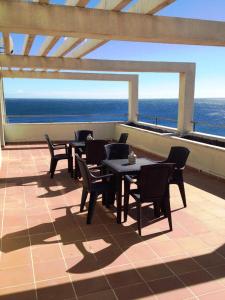 a patio with tables and chairs and the ocean at Ático Ancla in L'Ametlla de Mar