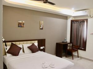 a bedroom with a bed and a table and a window at Waves Residency in Chennai +9 photos
