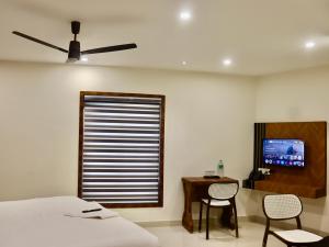 a bedroom with a bed and a table and a television at Waves Residency in Chennai