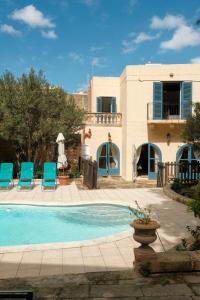 a house with a swimming pool and blue chairs at Historic Villa with a Private Pool in Mosta