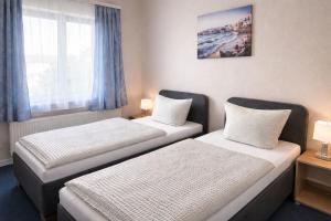 two beds in a hotel room with a window at Hotel KM in Darmstadt