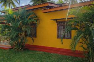 a yellow house with palm trees in front of it at Aqua Dream Adventures Resort in Trincomalee