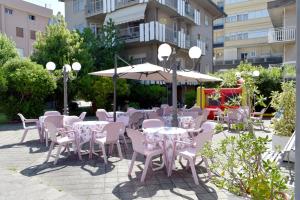 a patio with tables and chairs and an umbrella at Hotel Adriatico in Bellaria-Igea Marina