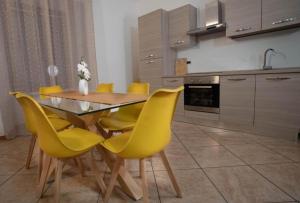a kitchen with a wooden table and yellow chairs at Slate House & Terrace - 6 min walk to Bernina Express in Tirano