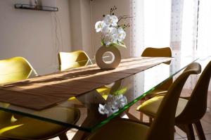 a table with yellow chairs and a vase with flowers on it at Slate House & Terrace - 6 min walk to Bernina Express in Tirano +7 photos