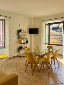 a dining room with a glass table and yellow chairs at Slate House & Terrace - 6 min walk to Bernina Express in Tirano