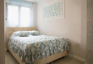 a bedroom with a bed with a comforter and a window at Apartman Nora Herceg Novi in Zelenika