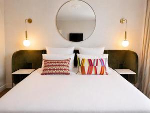 a bed with pillows and a mirror on the wall at Hôtel Restaurant Vaillant -ouverture Spa de 1200m2 Octobre 2026 in Sélestat