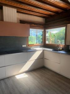 a kitchen with white cabinets and a sink and windows at lake view chalet Doussard Annecy in Doussard