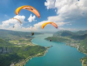 three paragliders are flying over a river at lake view chalet Doussard Annecy in Doussard