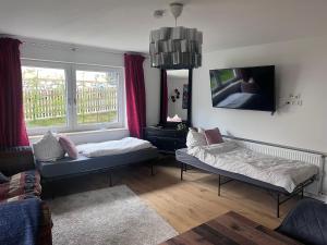 a living room with two beds and a tv at Landhaus Falkennest in Flintsbach am Inn
