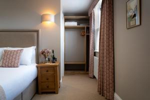 a hotel room with a bed and a night stand with a nightstand at The Bull Inn in Woodbridge