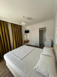 a bedroom with a large white bed and curtains at Tiffany Otel in Özdere