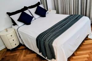 a bedroom with a white bed with blue pillows at Alphaville Serviced Apartment São Paulo in Barueri +36 photos