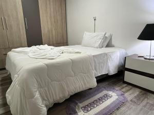 a bedroom with a white bed and a night stand at Mara e Jorge Suites Beira Mar in Cananéia