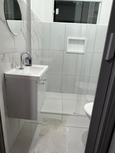 a white bathroom with a sink and a toilet at Mara e Jorge Suites Beira Mar in Cananéia