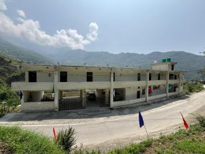 a building on a road with mountains in the background at The Jade Inn in Gopeshwar