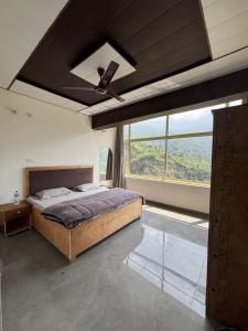 a bedroom with a bed and a large window at The Jade Inn in Gopeshwar